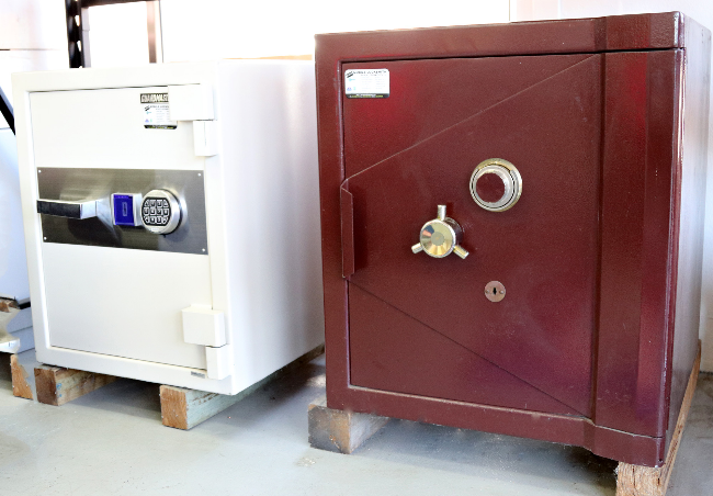 Two safes, one modern with digital lock and another vintage-style with mechanical dial, on a light-colored floor.