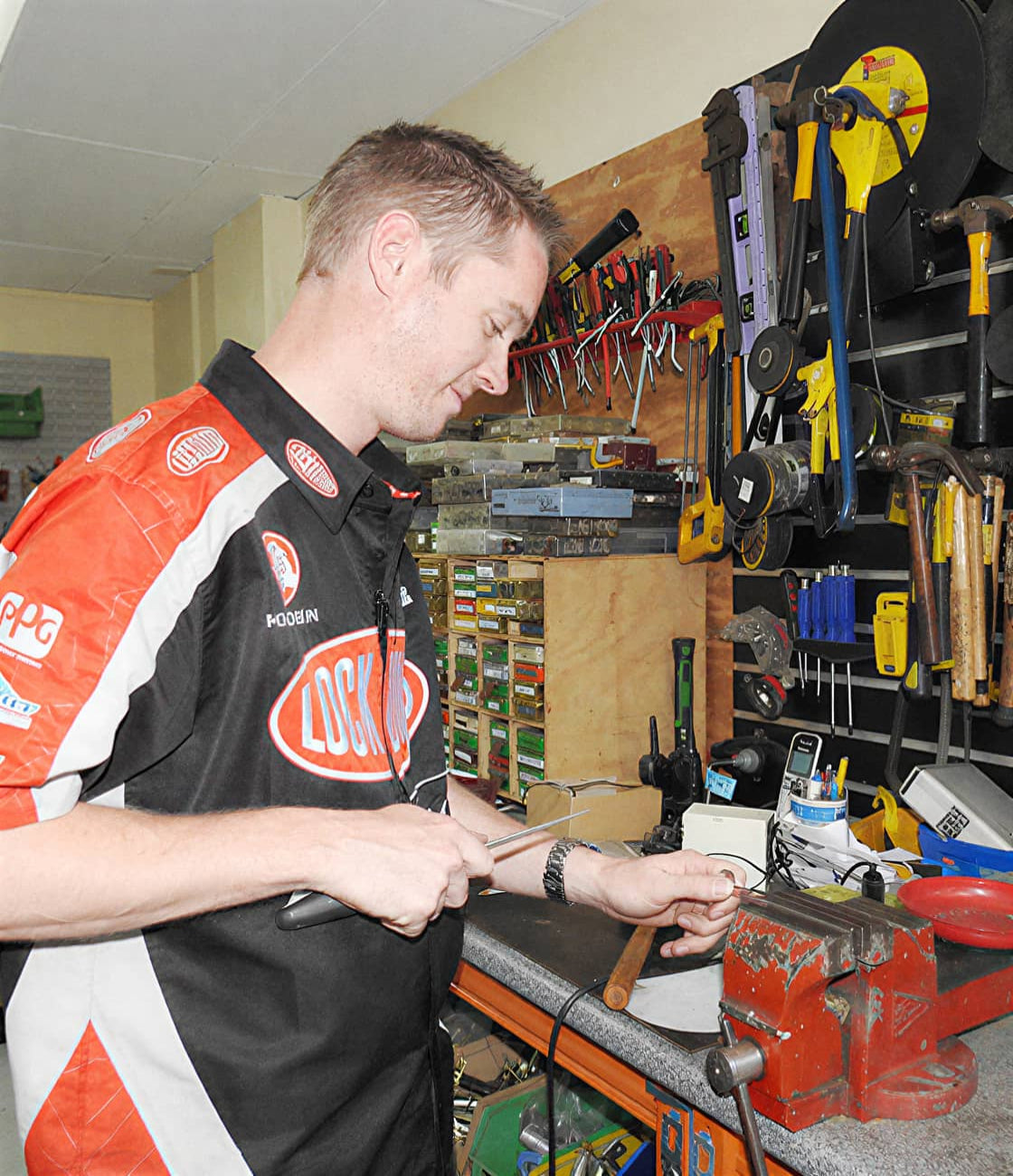 Person working in a locksmith workshop with tools and equipment around
